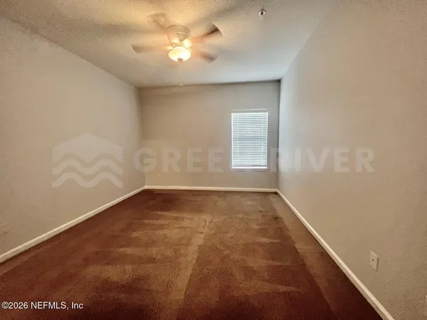 an empty room with windows and fan