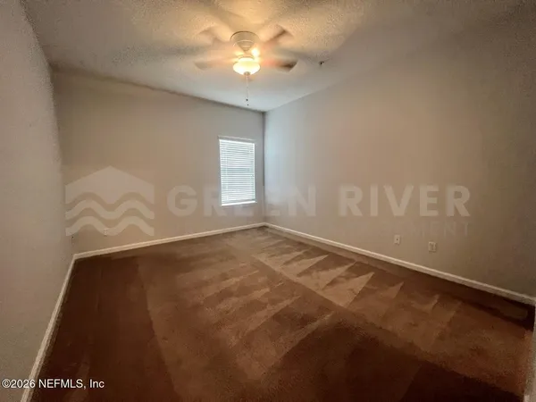 an empty room with windows and fan
