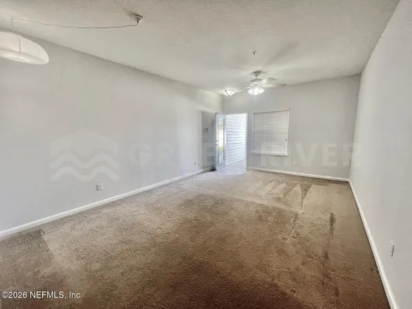 an empty room with a ceiling fan and carpet