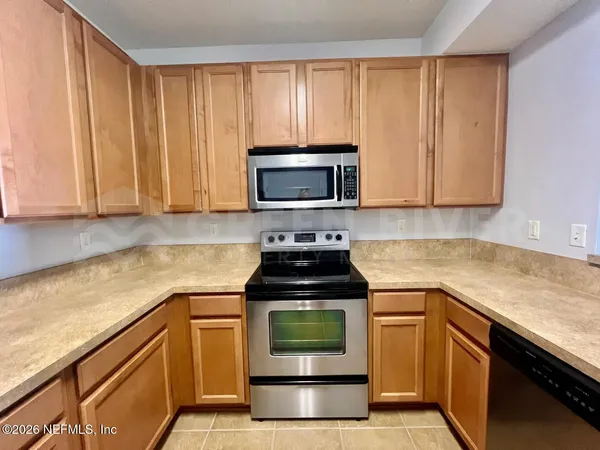 a kitchen with granite countertop a stove top oven microwave and cabinets
