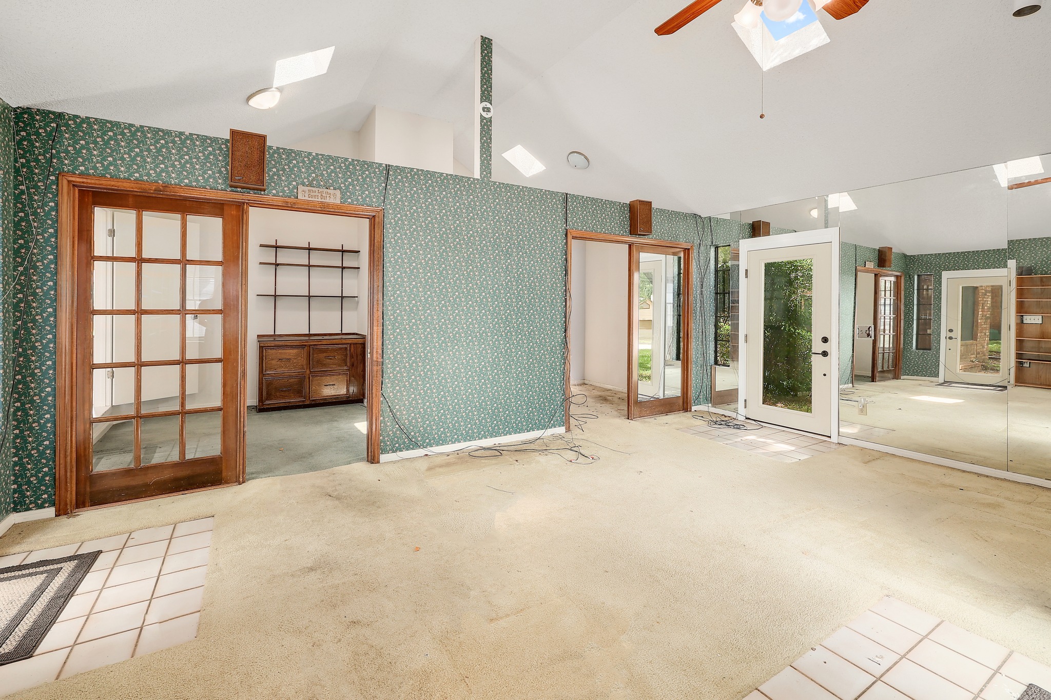 2202 Warfield Way Austin, TX 78728 - Photo 22 of 32 A spacious room features vaulted ceilings with skylights, French doors, and mirrored walls creating an open, airy ambiance.