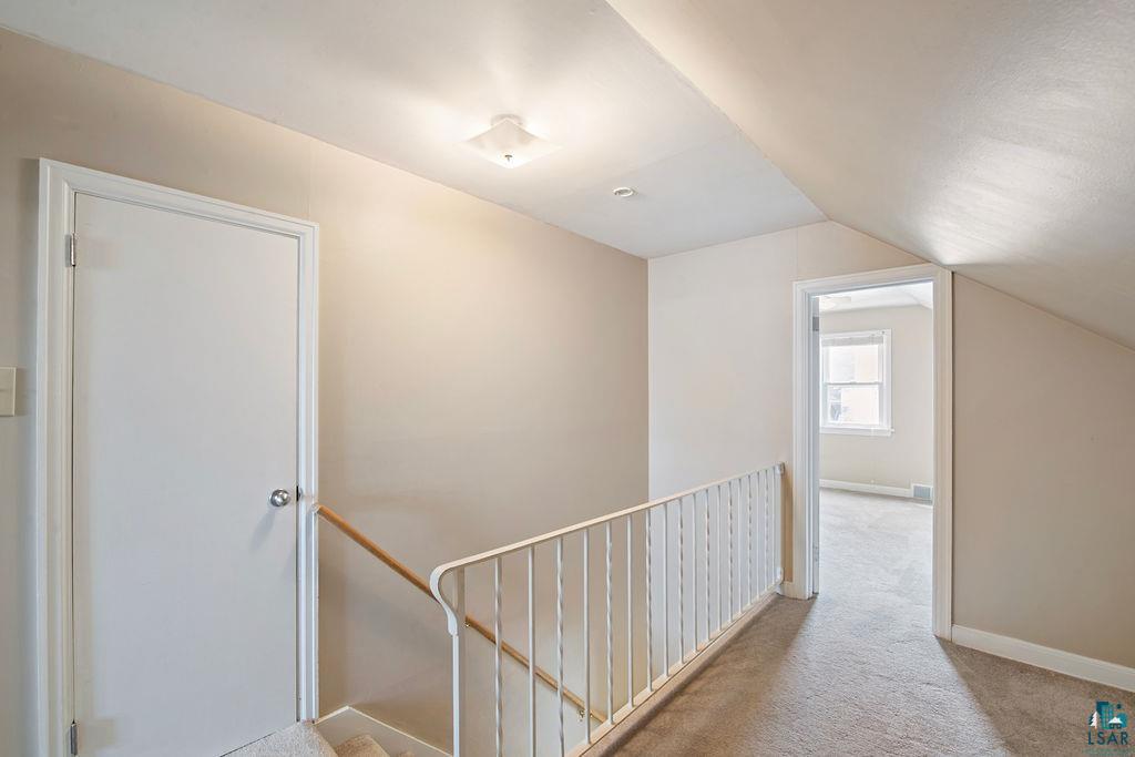 122 3rd Street Cloquet, MN 55720 - Photo 13 of 42 Carpeted hallway featuring a white metal railing and an overhead flush mount light fixture