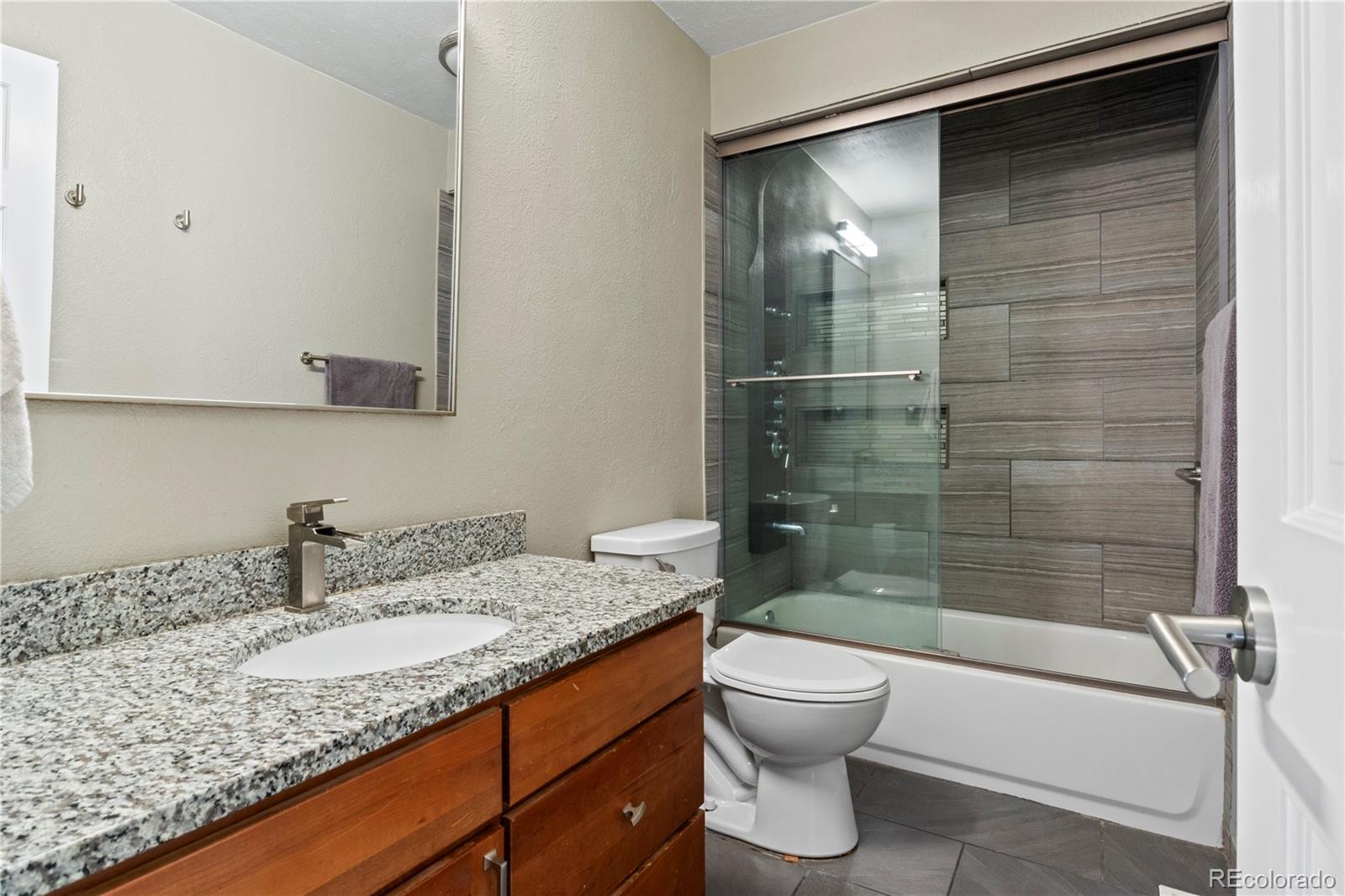 15780 Sandtrap Way Morrison, CO 80465 - Photo 22 of 36 a bathroom with a granite countertop sink toilet and shower