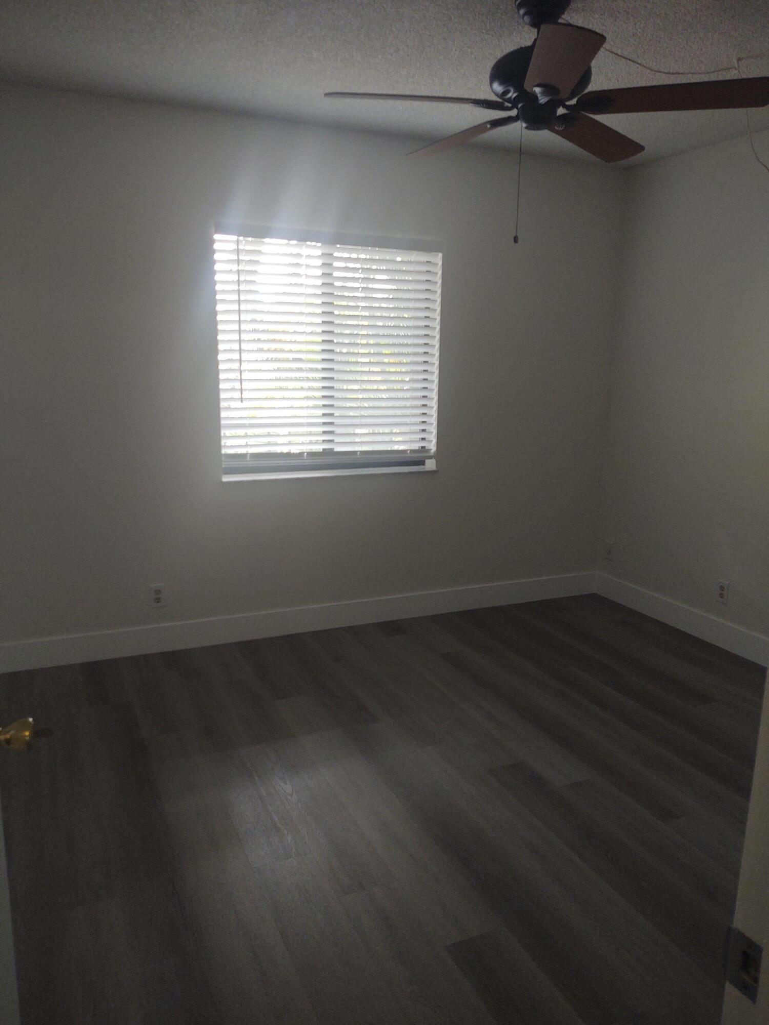 140 Northwest 70th Street, Unit 2040 Boca Raton, FL 33487 - Photo 12 of 18 an empty room with wooden floor fan and windows