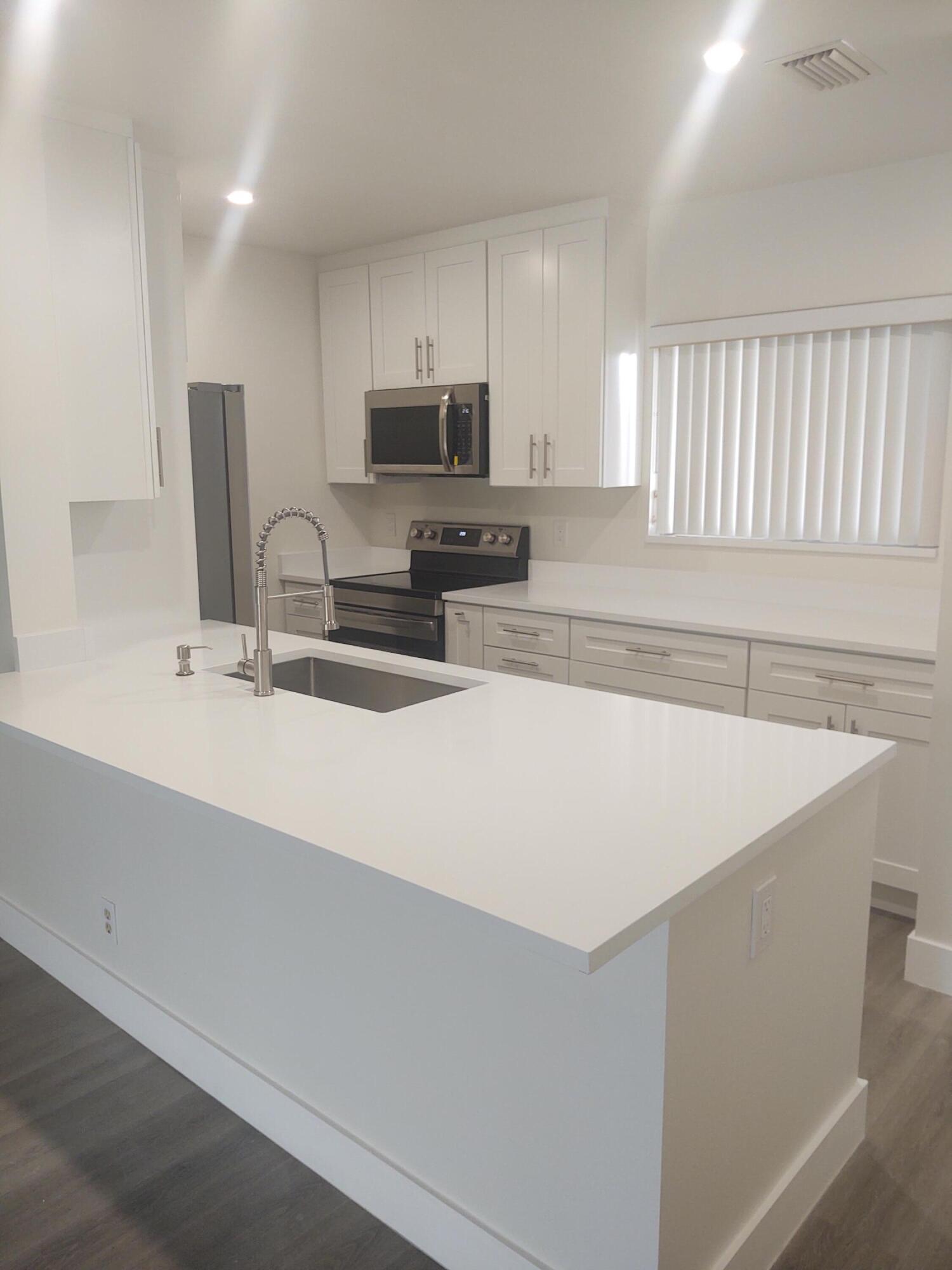 140 Northwest 70th Street, Unit 2040 Boca Raton, FL 33487 - Photo 2 of 18 a kitchen with stainless steel appliances a sink a stove a microwave a sink a refrigerator and cabinets