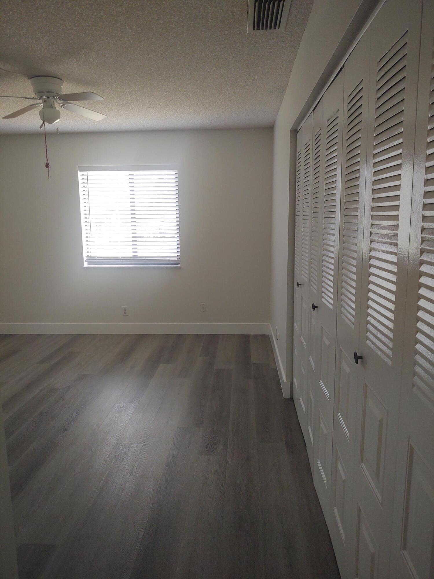 140 Northwest 70th Street, Unit 2040 Boca Raton, FL 33487 - Photo 10 of 18 an empty room with wooden floor and windows