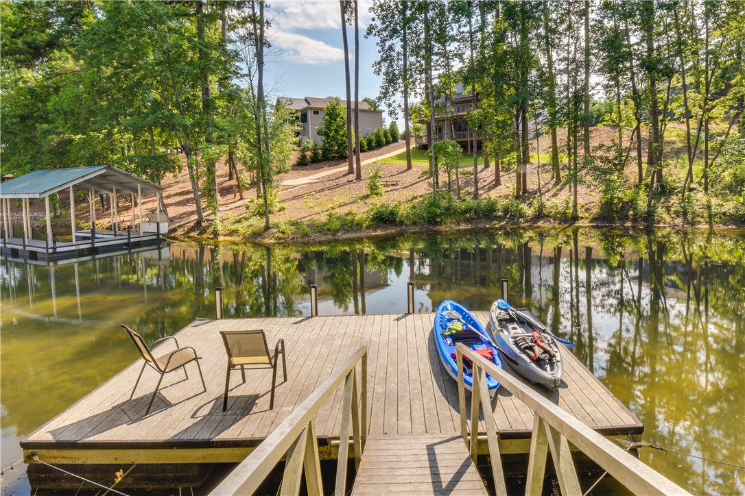 206 Petty Road Seneca, SC 29672 - Photo 5 of 48 A tranquil lakefront dock offers direct access to water recreation with a covered boat slip and wooded surroundings.