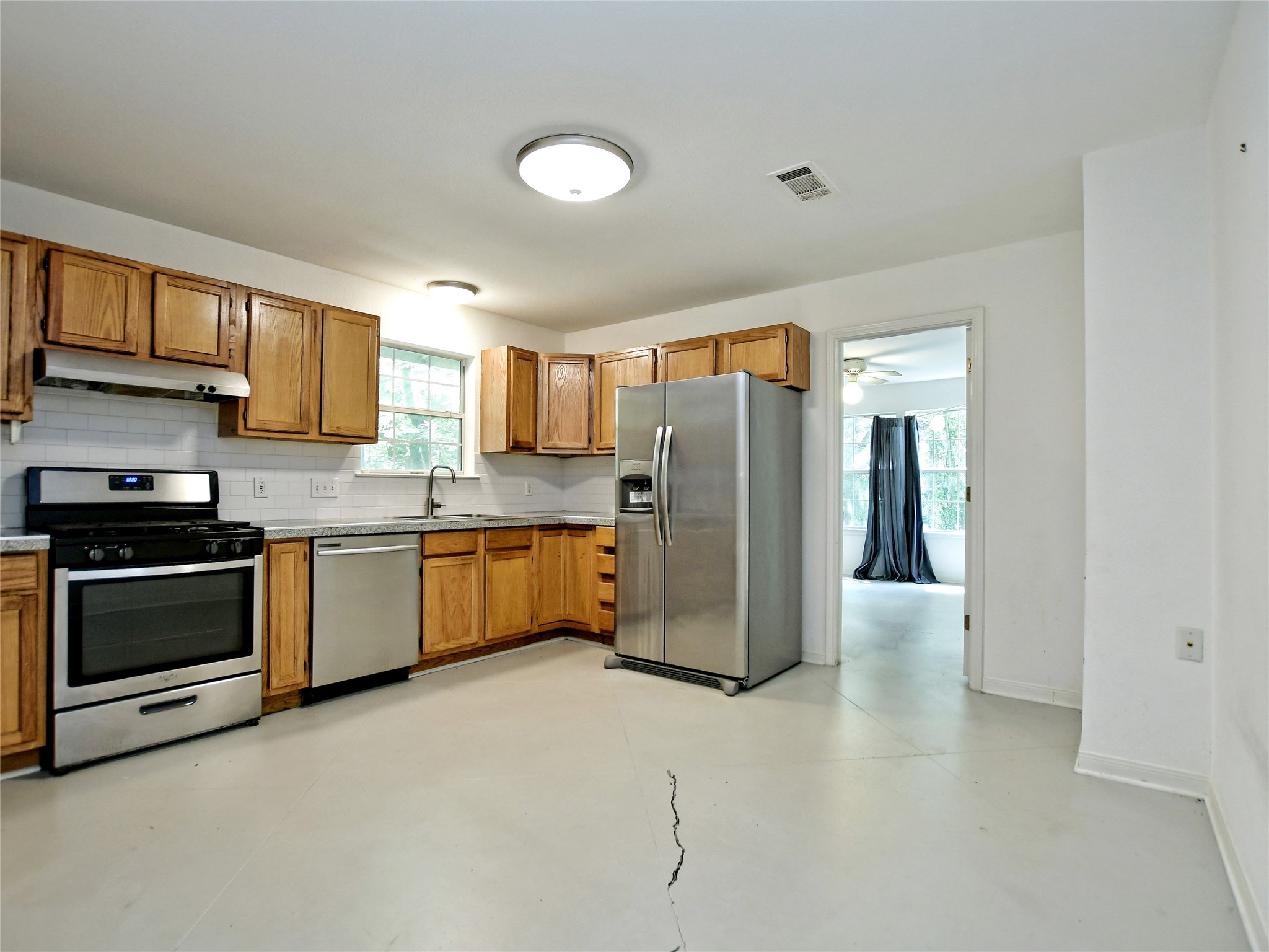 4604 Red River Street, Unit A Austin, TX 78751 - Photo 4 of 15 Kitchen featuring wood cabinetry, stainless steel appliances, white subway tile backsplash, and light-toned countertops