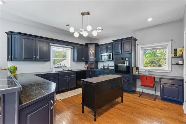 a kitchen with a stove a sink dishwasher a dining table and chairs with wooden floor