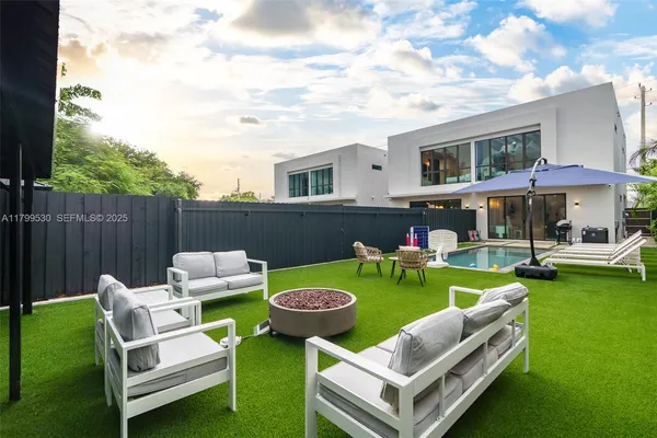 a view of a swimming pool and lounge chairs in back yard of the house