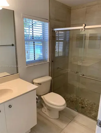 a bathroom with a toilet a sink a shower and a window