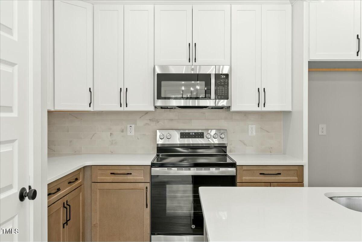 109 Averly Court Stem, NC 27581 - Photo 15 of 36 a kitchen with stainless steel appliances white cabinets and a stove top oven