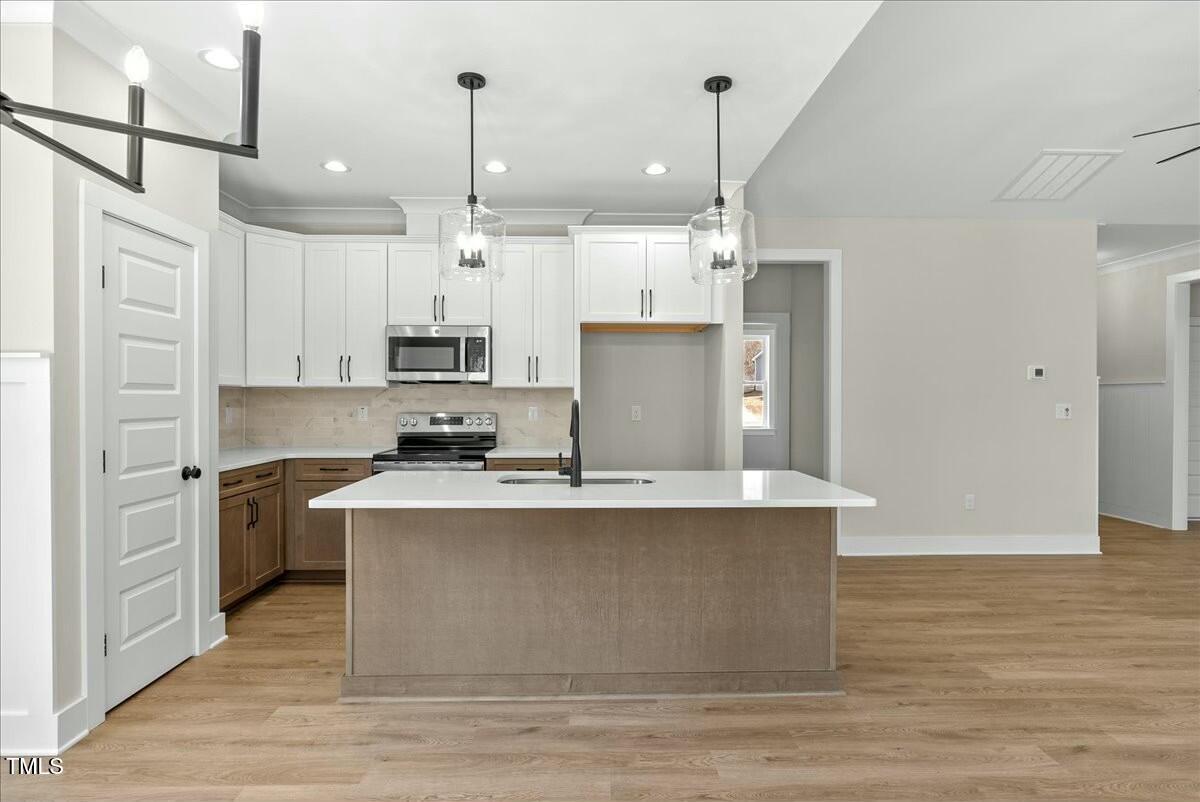 109 Averly Court Stem, NC 27581 - Photo 17 of 36 a kitchen with kitchen island a sink a stove a refrigerator and white cabinets