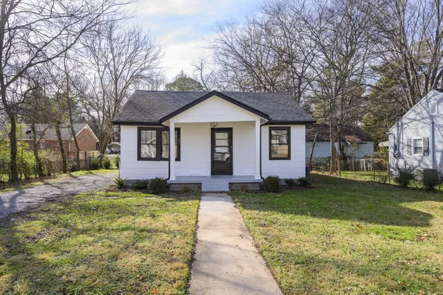 a front view of a house with a yard and trees