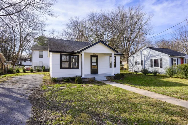 a view of a yard in front of a house with large trees
