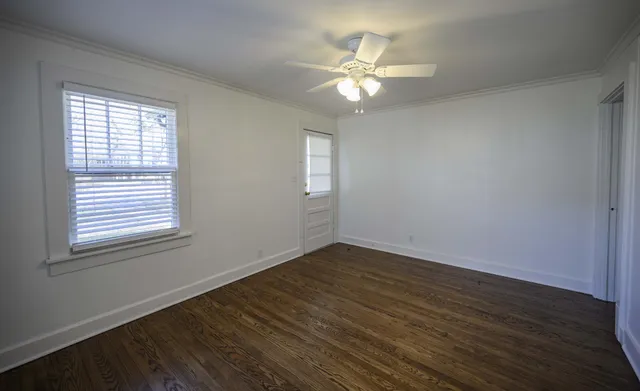 a view of an empty room with wooden floor and a window