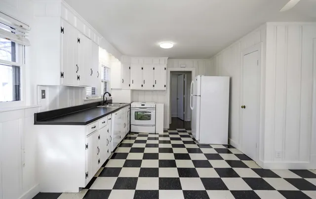 a kitchen with granite countertop white cabinets a refrigerator and a stove