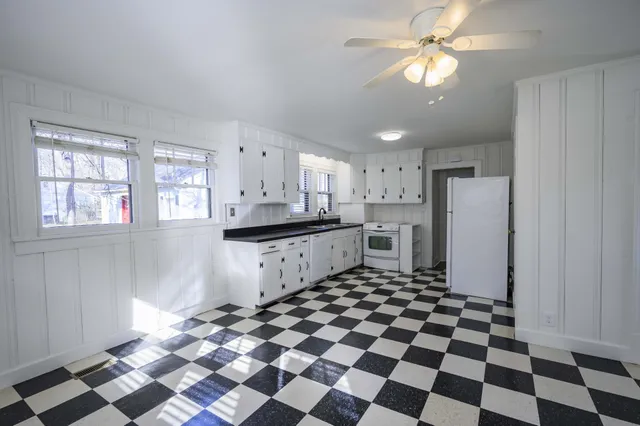 a kitchen with a checkered floor and white cabinets