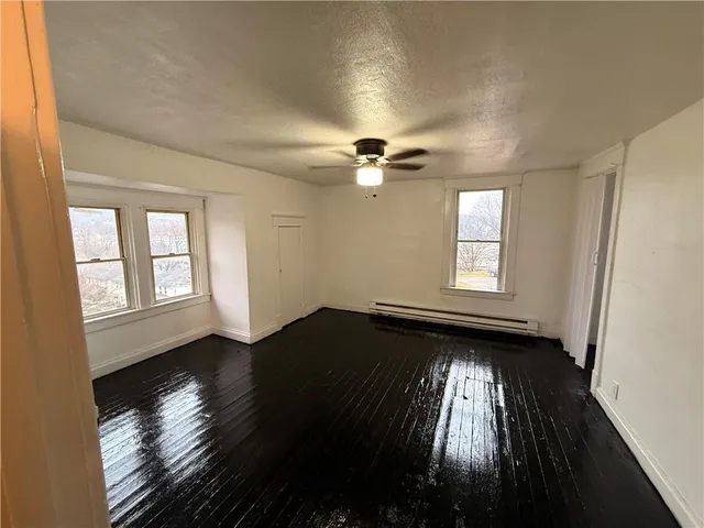 a view of empty room with wooden floor and fan