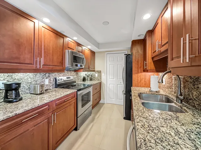 a kitchen with stainless steel appliances granite countertop a sink stove and refrigerator