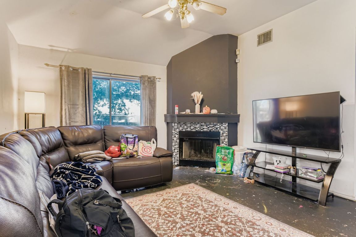 4705 Fallenash Drive Austin, TX 78725 - Photo 2 of 11 Living area with a tiled fireplace, vaulted ceiling, concrete floors, and ceiling fan