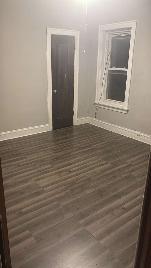 7842 South Bennett Avenue, Unit 2 Chicago, IL 60649 - Photo 5 of 10 a view of an empty room with wooden floor and a window