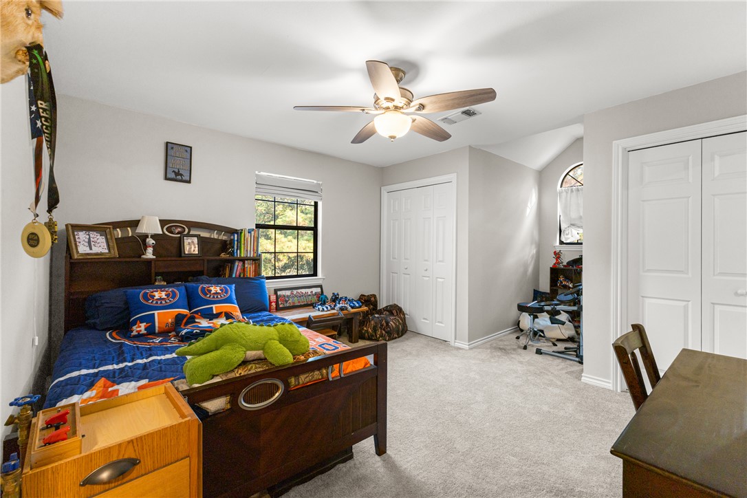 31928 Reids Prairie Road Waller, TX 77484 - Photo 25 of 43 Bedroom with light carpet, two closets, a ceiling fan, and an office area