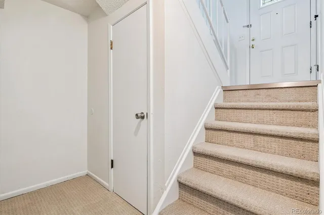 a view of staircase with white walls and white door