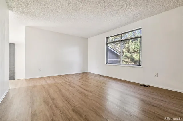 an empty room with wooden floor and windows