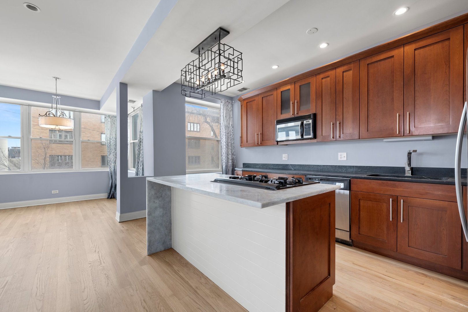 1122 North Oakley Boulevard, Unit C Chicago, IL 60622 - Photo 8 of 23 a kitchen with stainless steel appliances granite countertop a stove a sink dishwasher and a microwave oven with wooden floor