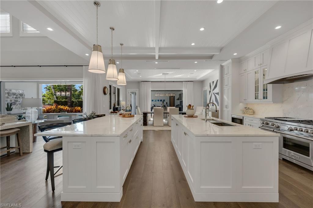 2025 Crayton Road Naples, FL 34102 - Photo 11 of 36 a large white kitchen with lots of counter space a sink appliances and a large window