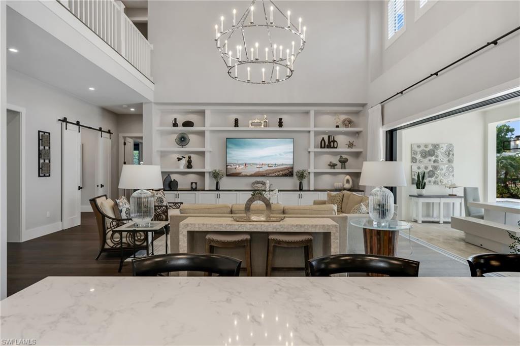 2025 Crayton Road Naples, FL 34102 - Photo 14 of 36 a living room with furniture a chandelier and a flat screen tv