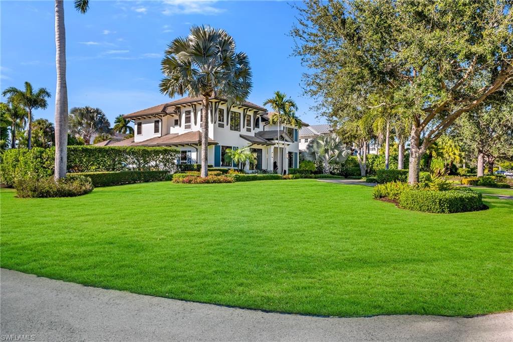 2025 Crayton Road Naples, FL 34102 - Photo 4 of 36 a view of a white house next to a yard with big trees
