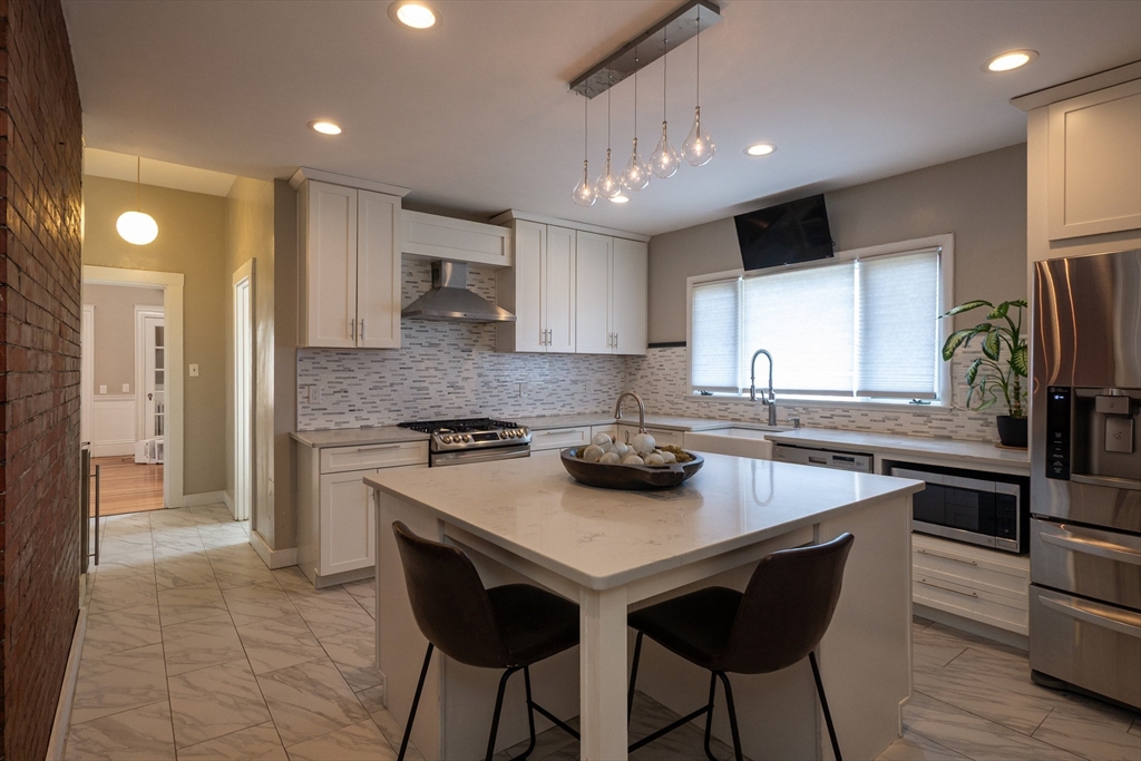 11 Wayne Street Boston, MA 02121 - Photo 9 of 27 a kitchen with stainless steel appliances granite countertop a stove a sink a refrigerator and a microwave