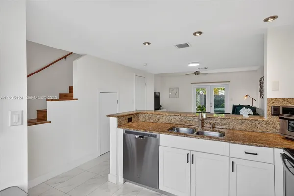 a kitchen with stainless steel appliances granite countertop a sink and dishwasher with white cabinets