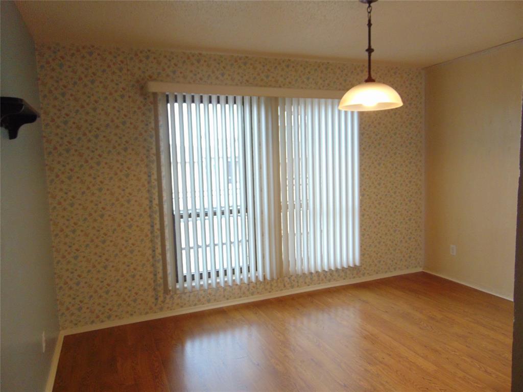 12806 Midway Road, Unit 2020 Dallas, TX 75244 - Photo 4 of 18 a view of an empty room with wooden floor and a window