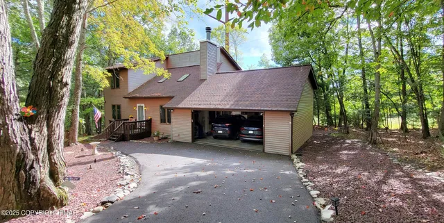 a view of a house with a yard and large tree