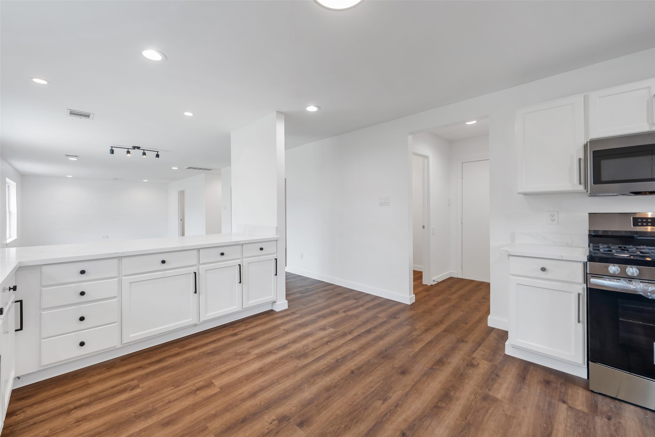 11703 North Perry Avenue Houston, TX 77071 - Photo 17 of 43 a large kitchen with white cabinets stainless steel appliances and wooden floor