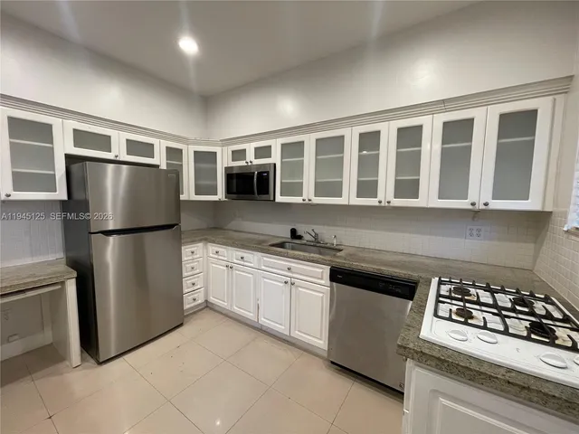 a kitchen with stainless steel appliances granite countertop a refrigerator sink and stove
