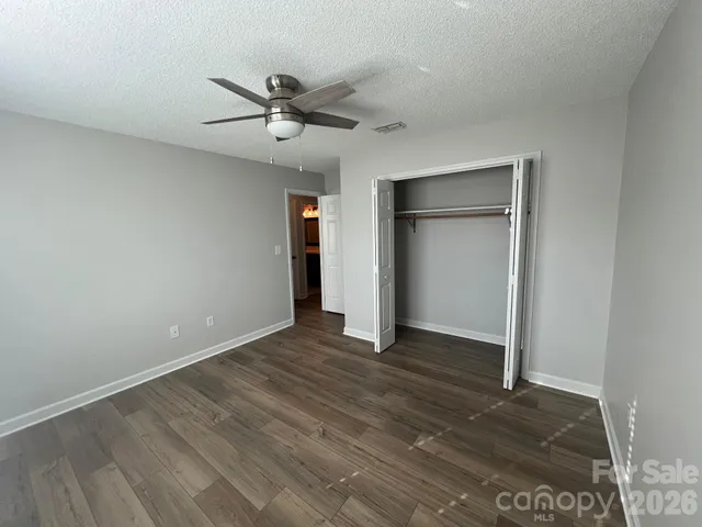 an empty room with wooden floor closet and fan