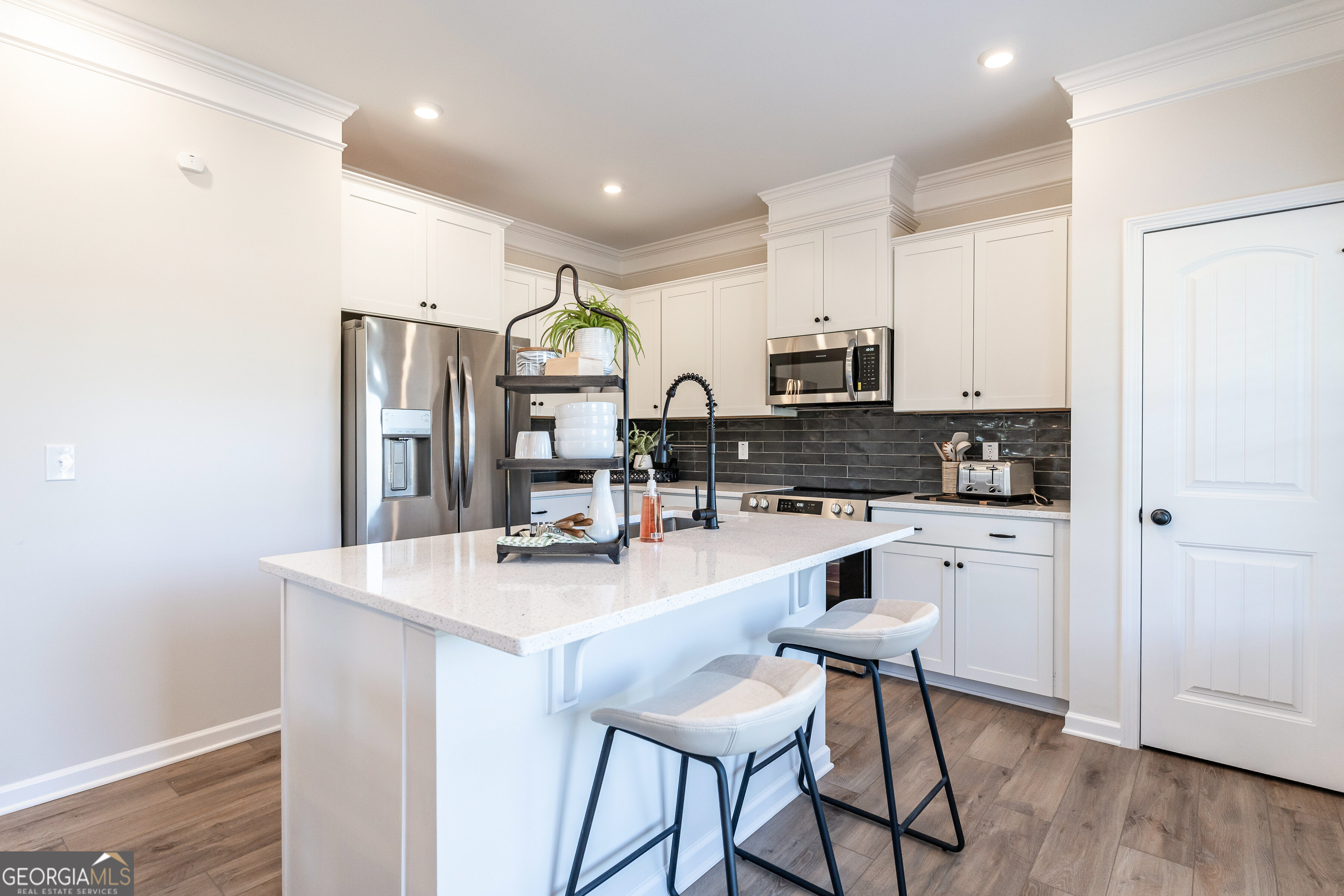 10410 Trellis Lane, Unit (LOT 35) Hampton, GA 30228 - Photo 17 of 28 a kitchen with stainless steel appliances granite countertop a stove a sink a refrigerator a microwave oven with white cabinets and wooden floor