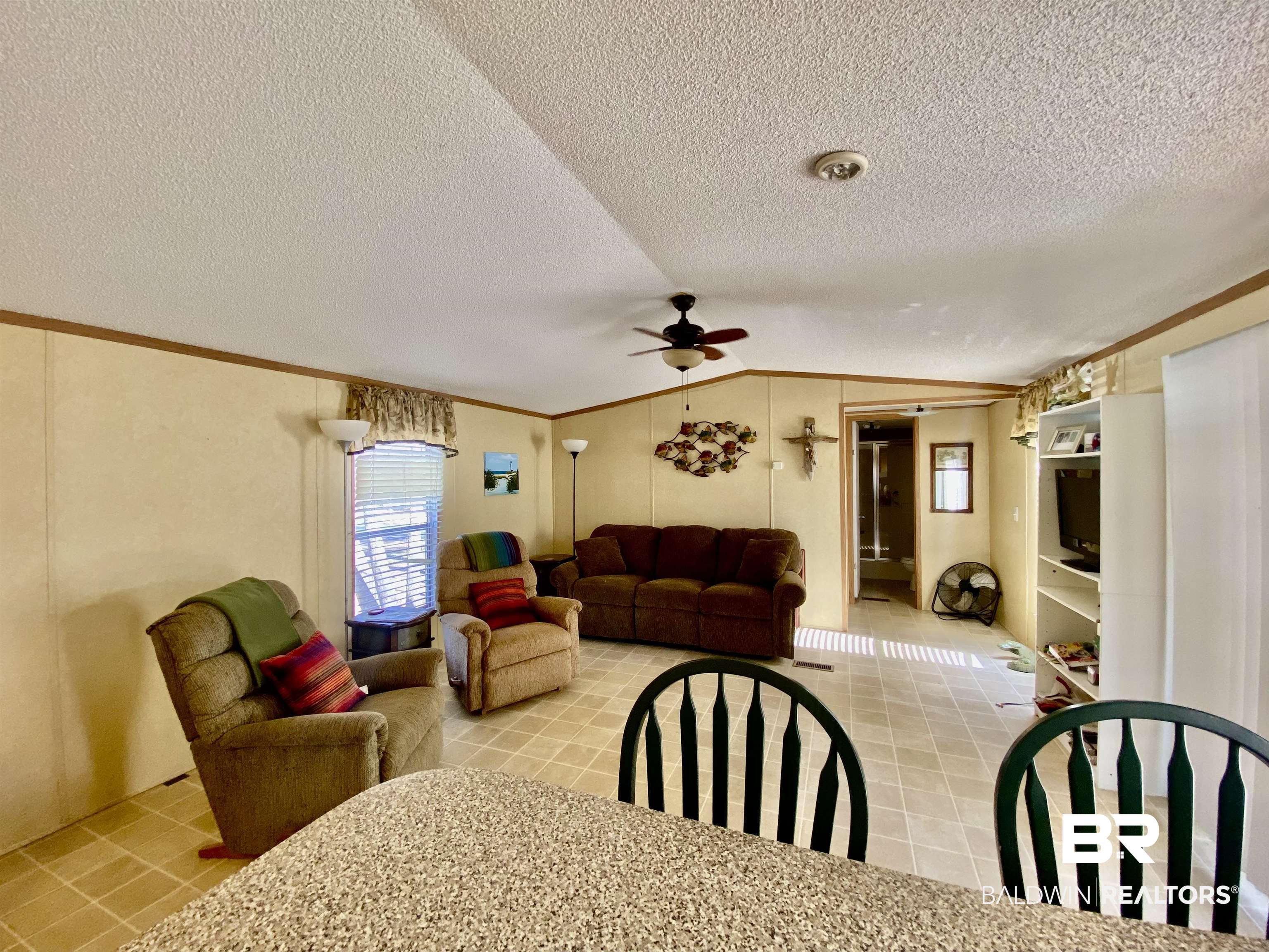 294 Eureka Way Uriah, AL 36480 - Photo 6 of 18 Dining room featuring light tile patterned floors, ceiling fan, ornamental molding, vaulted ceiling, and a textured ceiling