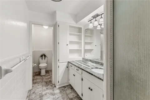 a bathroom with a granite countertop sink a toilet and a shower