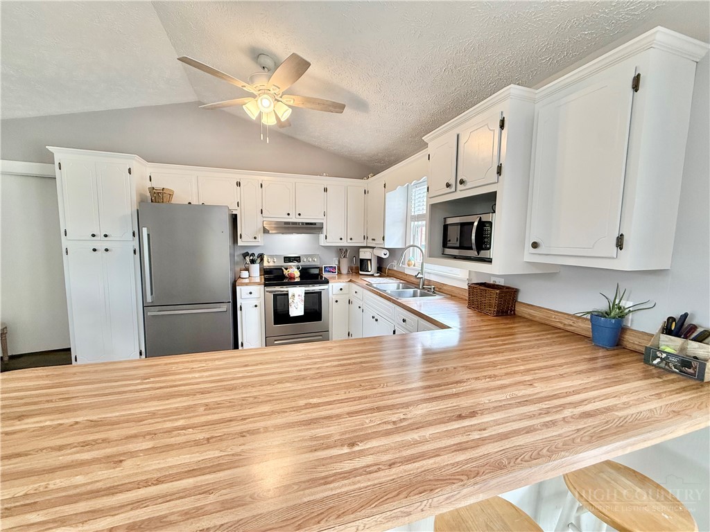 1315 Irwin Grocery Road Laurel Springs, NC 28644 - Photo 8 of 22 a kitchen with stainless steel appliances kitchen island granite countertop a refrigerator a stove oven with white cabinets and wooden floor