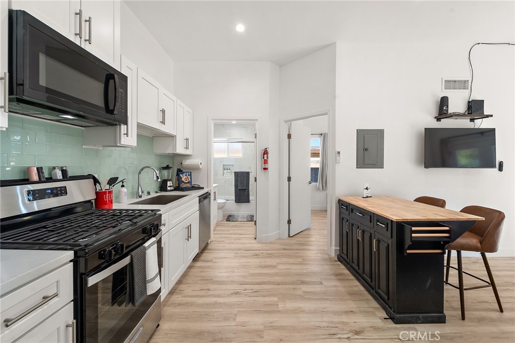 10730 Strathern Street Sun Valley, CA 91352 - Photo 45 of 57 a kitchen with stainless steel appliances a stove top oven a sink a refrigerator white cabinets and wooden floor