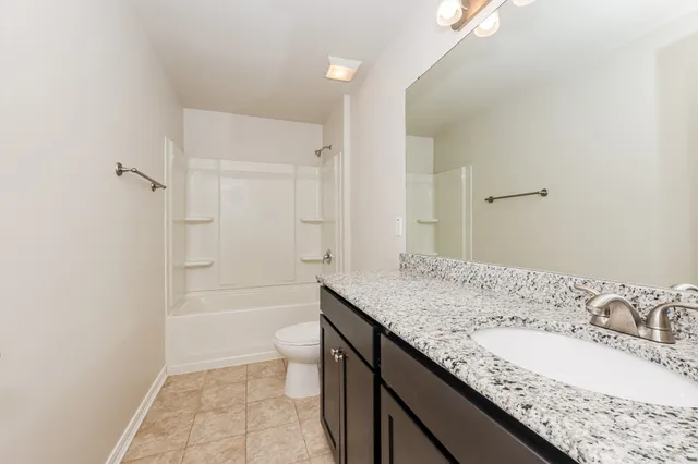 a bathroom with a granite countertop sink a toilet and shower