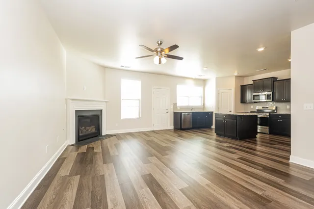 a view of a kitchen with furniture a ceiling fan and wooden floor
