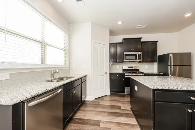 a kitchen with a granite countertop sink stainless steel appliances and window
