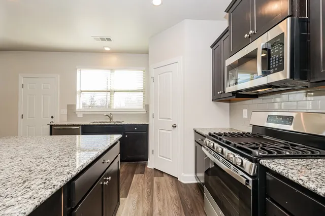 a kitchen with stainless steel appliances granite countertop a stove a microwave and wooden cabinets