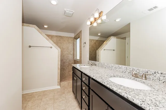 a bathroom with a granite countertop double vanity sink and a mirror